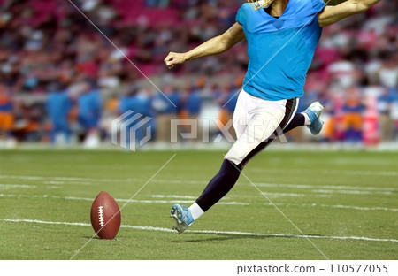 American football player kicking ball in the stadium field 110577055