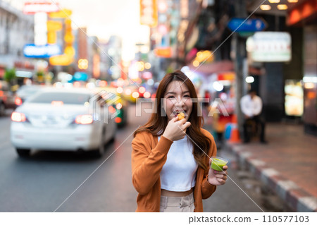 Young Asian tourists standing and eating Thai desserts 110577103