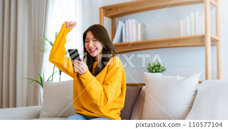 Happy young asian woman relax on comfortable couch at home texting messaging on smartphone Happy young asian woman relax on comfortable couch at home texting messaging on smartphone 110577104