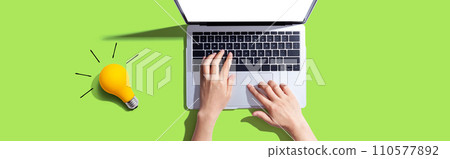 Person using a laptop computer and a light bulb 110577892