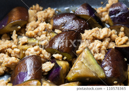 A cooking scene of frying eggplant and ground chicken in a frying pan. A cooking scene of frying eggplant and ground chicken in a frying pan. 110578365
