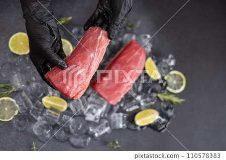 Chef holding piece of Fresh cooled tuna Fish fillet over pieces of ice Chef holding piece of Fresh cooled tuna Fish fillet over pieces of ice 110578383