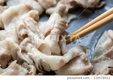 A cooking scene where pork belly (thinly sliced) is stir-fried in a frying pan. 110578412
