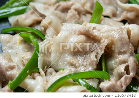 A cooking scene where pork belly and green pepper are stir-fried in a frying pan. 110578418