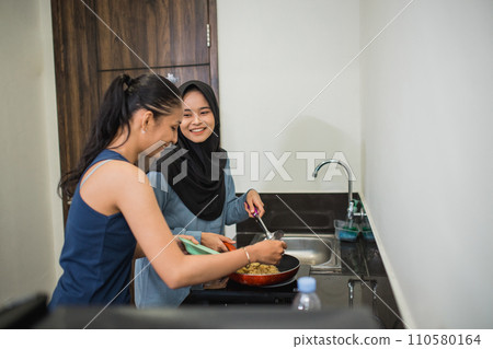 friendship of two multireligious girls cooking together in the kitchen friendship of two multireligious girls cooking together in the kitchen 110580164