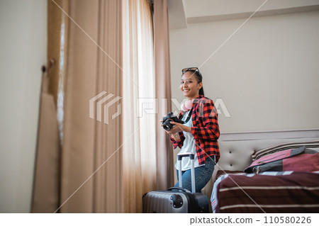 smiling female local tourist holding a camera to take pictures from window 110580226