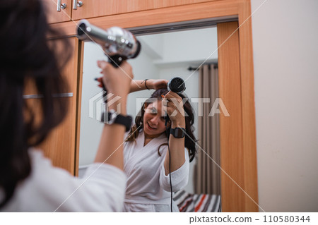 attractive girl wearing white bath robe using hair dryer 110580344