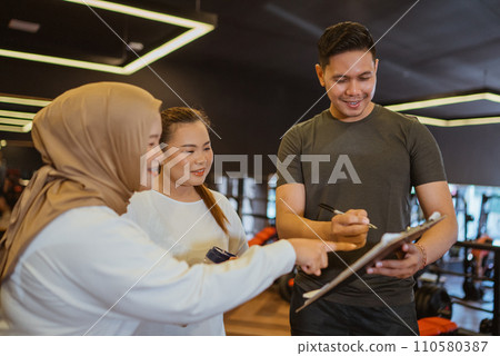 male instructor explaining trainee workout plan 110580387