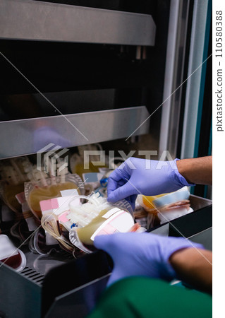 doctor's hand with rubber glove removing blood bag from storage 110580388
