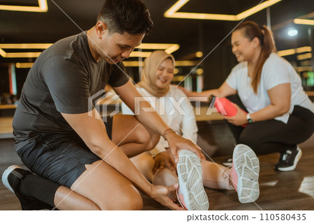 asian male instructor helping sprained ankle trainee 110580435