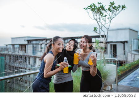 three young ladies chatting in sportswear holding a drink after exercise three young ladies chatting in sportswear holding a drink after exercise 110580558