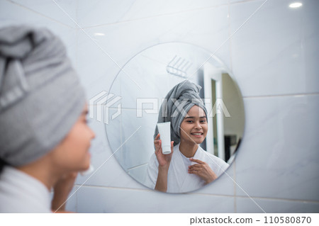 smiling girl with bathrobe seen from the reflection of the mirror smiling girl with bathrobe seen from the reflection of the mirror 110580870