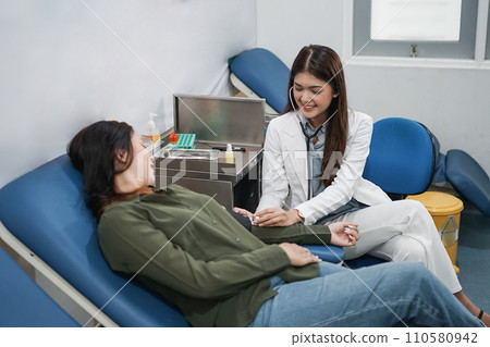 Beautiful female doctor sits when examining patient using stethoscope Beautiful female doctor sits when examining patient using stethoscope 110580942