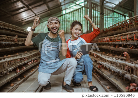excited male and female workers with hands up holding tablet 110580946