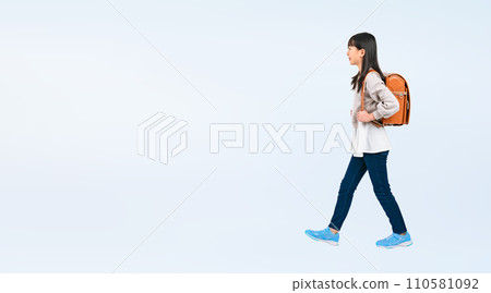 Female elementary school student walking with a school bag on her back 110581092