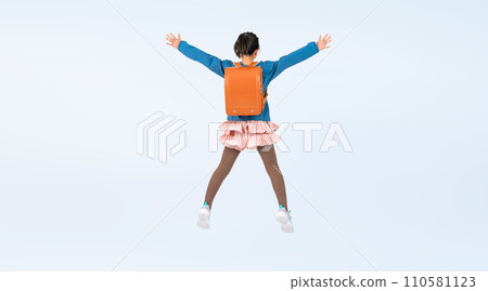 Elementary school girl jumping with a school bag on her back Elementary school girl jumping with a school bag on her back 110581123