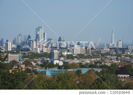 Scenic view of London cityscape with blue sky in background. Modern skyscrapers amidst residential buildings. High angle view of urban development in London. Scenic view of London cityscape with blue sky in background. Modern skyscrapers amidst residential buildings. High angle view of urban development in London. 110583649