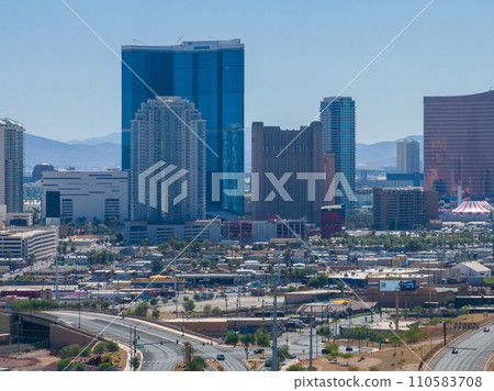 Aerial view of Las Vegas cityscape with modern skyscrapers, diverse architecture, bustling streets, and mountains under a clear blue sky, showcasing urban vibrancy and design. 110583708