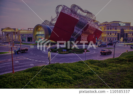 Luxurious shopping mall in Katara cultural village in Doha Qatar exterior sunset shot showing the entrance  with people and cars in the street 110585337