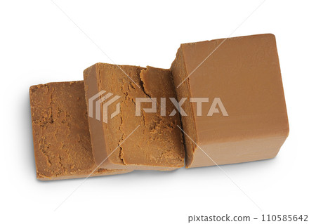 Brown cheese. Norwegian brunost isolated on white background. Top view. Flat lay Brown cheese. Norwegian brunost isolated on white background. Top view. Flat lay 110585642