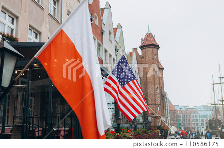 US and Polish flags fluttering in the wind on the building, old town 110586175