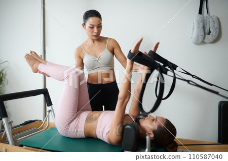 Fit young woman doing core exercise in special machine under control on coach Fit young woman doing core exercise in special machine under control on coach 110587040
