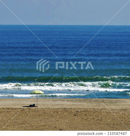 waves and umbrellas on the coast 110587487