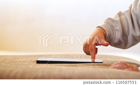 Child's finger pressing, scrolling, tapping on mobile phone screen. Little child learns to use new technologies. Baby pressing with finger on phone touch screen, close-up and soft focus. 110587551