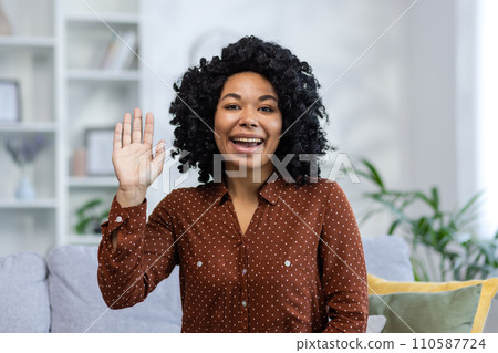 Close-up portrait of a young African American woman greeting, waving and talking to the camera. Close-up portrait of a young African American woman greeting, waving and talking to the camera. 110587724
