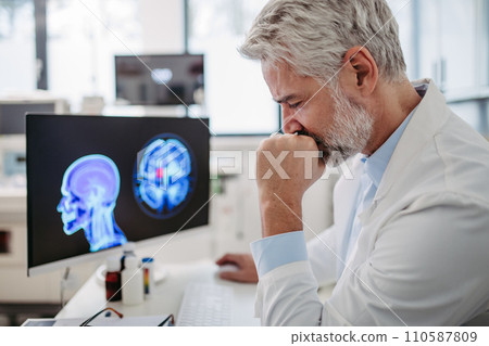 Sad doctor looks at an MRI scan, patient's bad test results, feeling helpless. Recurrence of the disease 110587809