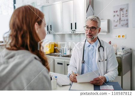 Doctor discussing test results with teenage girl, explaining diagnosis and medication usage. Concept of preventive health care for adolescents. 110587812