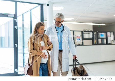 Pregnant woman in pain talking to obstetrician in hospital. Admitting woman in labor to maternity ward, planned cesarean section delivery. 110587877