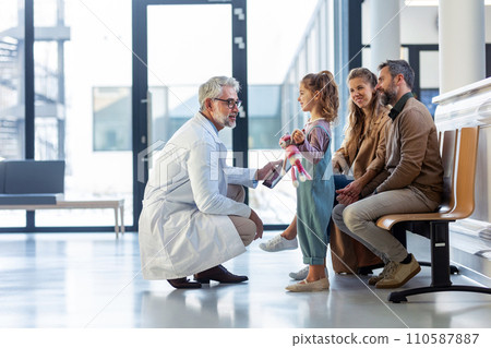 Doctor explaining results of MRI scan of brain to parents of young girl patient, delivering good news. Diagnosis of diseases and head injuries. Doctor explaining results of MRI scan of brain to parents of young girl patient, delivering good news. Diagnosis of diseases and head injuries. 110587887