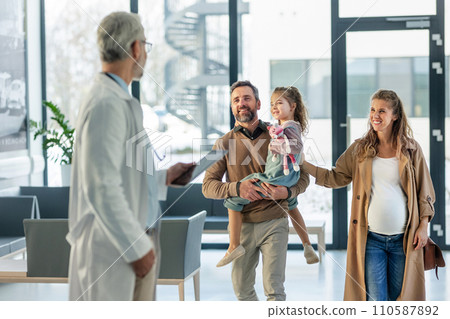 Girl patient looking forward to her doctor and examination in a modern clinic. Girl arriving in hospital with her parents. Emotional support during medical examination. Girl patient looking forward to her doctor and examination in a modern clinic. Girl arriving in hospital with her parents. Emotional support during medical examination. 110587892