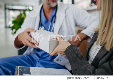 Pharmaceutical sales representative presenting new medication to doctor in medical building. 110587930