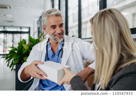 Pharmaceutical sales representative presenting new medication to doctor in medical building. 110587933