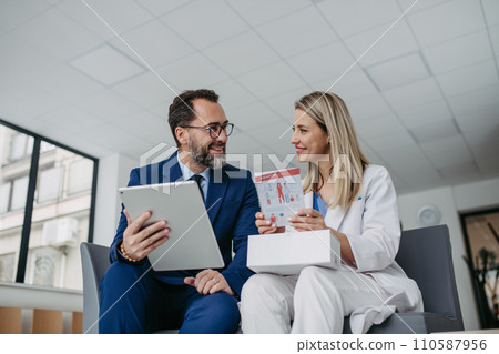 Pharmaceutical sales representative talking with doctor in medical building. Ambitious male sales representative presenting new medication. 110587956
