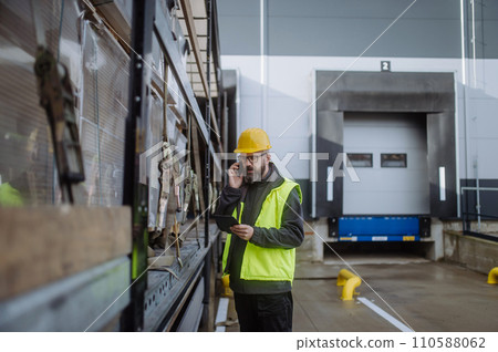 Warehouse receivers unloading of the truck in front of warehouse, phone calling checking delivered items. Warehouse receivers unloading of the truck in front of warehouse, phone calling checking delivered items. 110588062