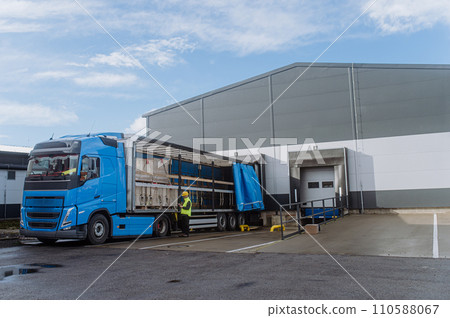 Warehouse receiver standing by blue truck, holding tablet, looking at cargo details, checking delivered items, goods against order. Warehouse receiver standing by blue truck, holding tablet, looking at cargo details, checking delivered items, goods against order. 110588067