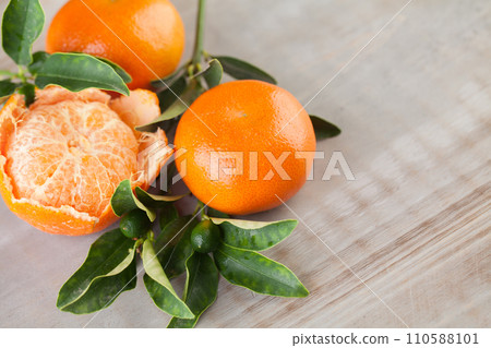 Organic tangerine with green leaves on grey wooden board table 110588101