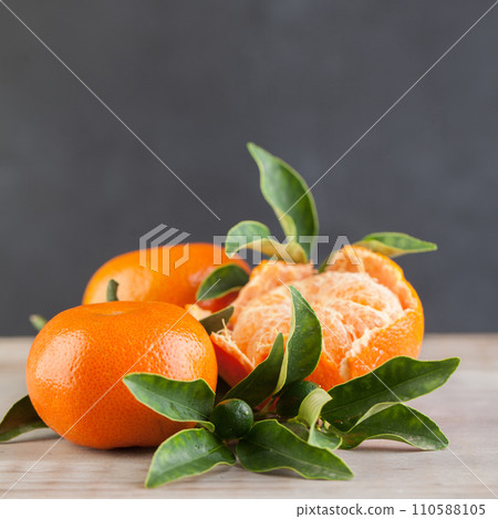 Clementine or tangerine with green leaves on gray wooden board table background Clementine or tangerine with green leaves on gray wooden board table background 110588105