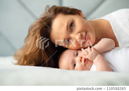 Happy Mother with her newborn baby. Closeup portrait of a loose haired loving mother with her child. Young mom with a beautiful infant child at home. Mum loves her infant son. Happy Mother with her newborn baby. Closeup portrait of a loose haired loving mother with her child. Young mom with a beautiful infant child at home. Mum loves her infant son. 110588265