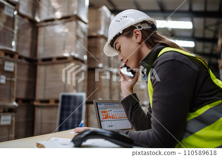 Warehouse worker checking delivery, stock in warehouse on computer, pc, while phone calling with contractor. Warehouse manager using warehouse management software, app. Warehouse worker checking delivery, stock in warehouse on computer, pc, while phone calling with contractor. Warehouse manager using warehouse management software, app. 110589618