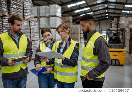 Warehouse workers reading product order, order picking. Warehouse manager checking delivery, stock in warehouse, inspecting products for shipment. 110589657