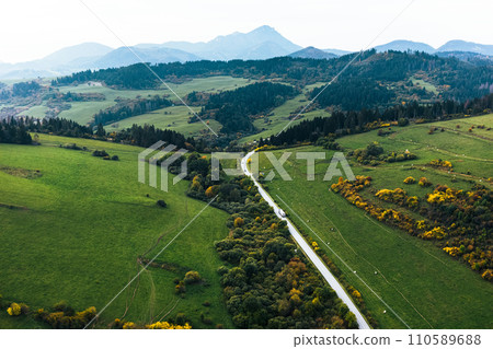 Aerial view of green summer farm fields, crops or pasture with road. Aerial view of green summer farm fields, crops or pasture with road. 110589688