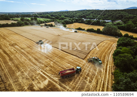 Aerial view of a tractor and harvester working in a field. Agriculture and cultivation of industrial farms. Agribusiness. 110589694
