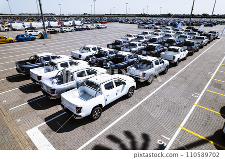 Aerial view of a massive parking lot at a car manufacturing facility with newly produced vehicles parked in rows. Aerial view of a massive parking lot at a car manufacturing facility with newly produced vehicles parked in rows. 110589702