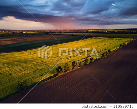 Aerial view of green summer farm fields, crops or pasture with during sunset. Aerial view of green summer farm fields, crops or pasture with during sunset. 110589715