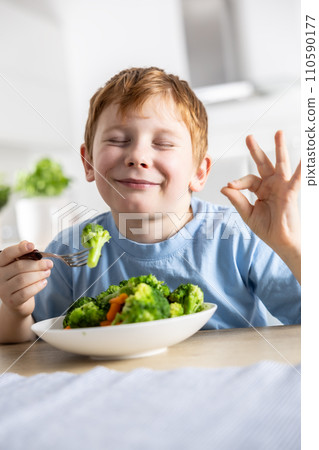 A cute little boy is eating broccoli for lunch and he likes it very much A cute little boy is eating broccoli for lunch and he likes it very much 110590177