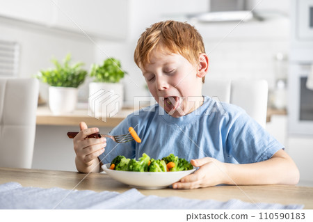 The little boy looks with distaste at the carrot on his fork The little boy looks with distaste at the carrot on his fork 110590183